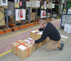Mat in the Casey Green store applying RTA stickers to a row of 6 boxes