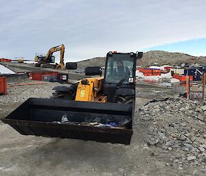 A front end loader transports rubbish after it is collected