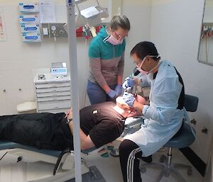 A visiting dentist does a dental treatments on an expeditioner