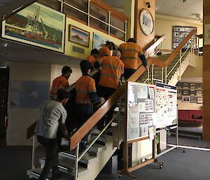 The new treadmill gets lifted up the stairs by a group of people into place