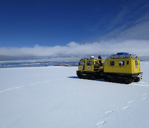 A yellow Hägglunds with an ocean view in the background