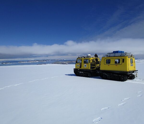 A yellow Hägglunds with an ocean view in the background