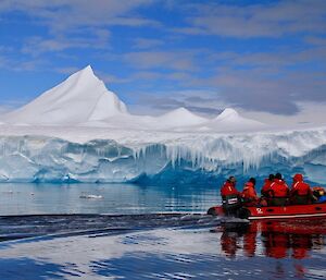 Expeditioners in an IRB near a large iceberg