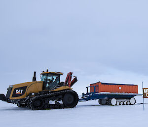 Tractor vehicle towing a shipping container in front of the Antarctic Circle sign