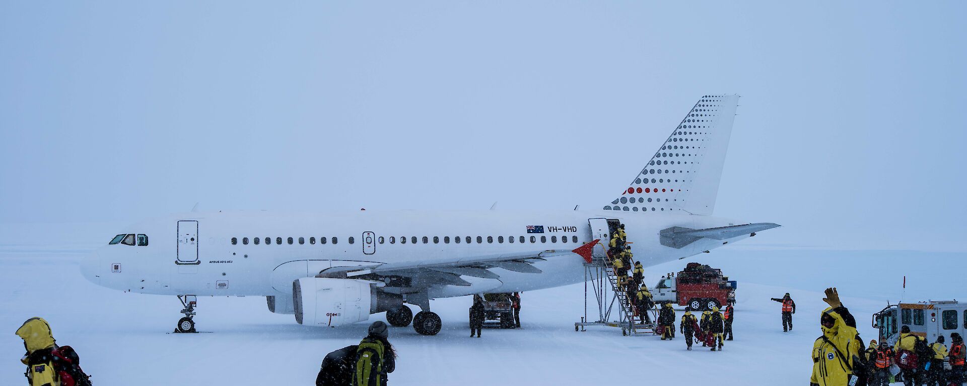 The A319 aircraft on the ice runway being boarded by expeditioners in yellow suits