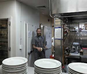 Expeditioner standing in kitchen with plates in foreground