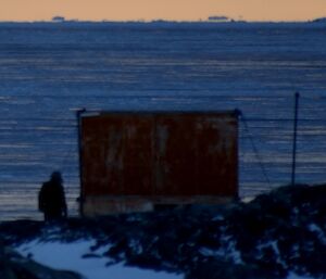 Dark shape of person near hut