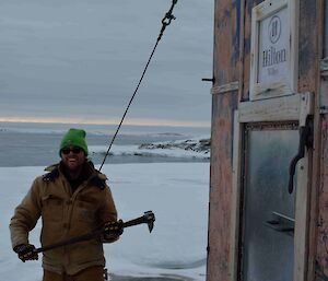 An expeditioner standing beside a hut