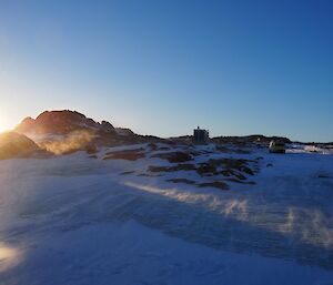 Browning Hut and Hägglunds vehicle amongst a rocky hill at sunset