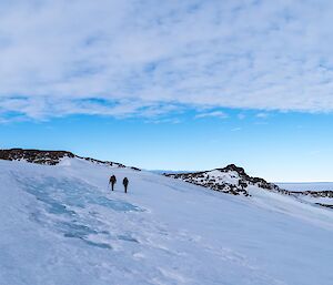 Two expeditioners hiking up a snow covered slope