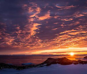 A fiery sky over icebergs and cliffs