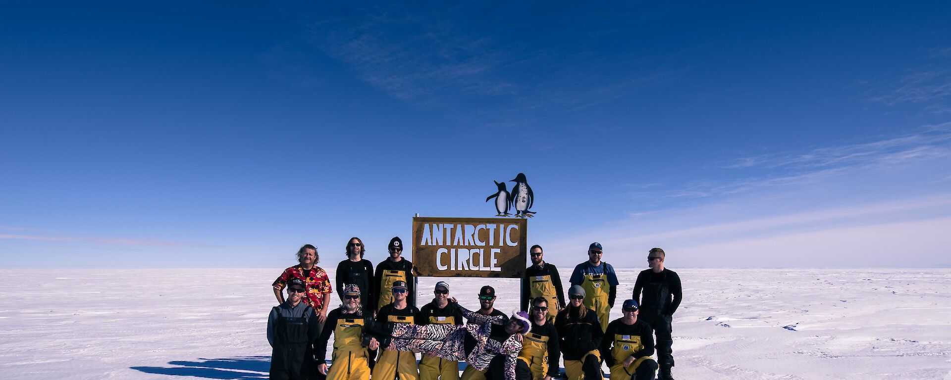Group of expeditioners at Antarctic Circle sign