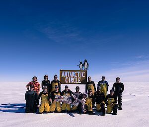 Group of expeditioners at Antarctic Circle sign