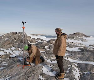 Two expeditioners on rocks with anemometer