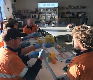 Expeditioners sitting around a table injecting oranges