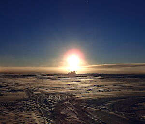 Ice runway with bulldozers and a ring around the sun
