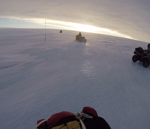 Quads driving on ice with blowing snow