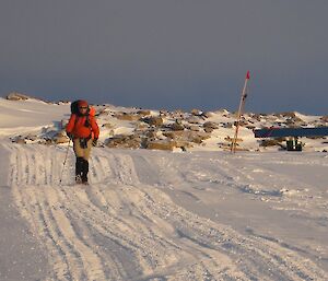Man in orange jacket hiking along snow road