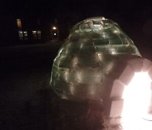 An igloo at night with hlights inside glowing throiugh the walls