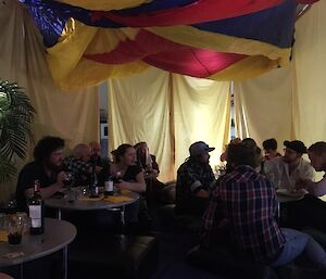 Expeditioners sitting in a homemade tent inside a building