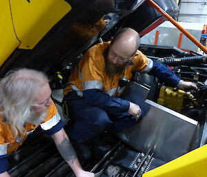 Two expeditioners looking at engine