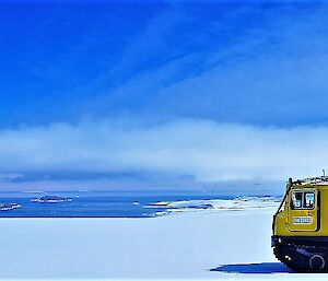 Yellow Hägglunds on snow with blue sky