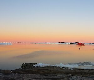 Aurora Australis ship on flat sea and orage sky