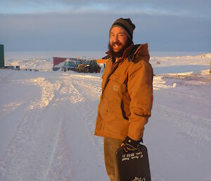 Expeditioner in brown jacket standing put in the snow in the sunshine