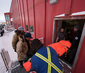 Moving a stretcher into the red shed