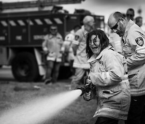 Ashleigh holding fire hose and laughing