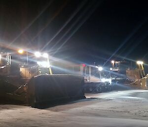 Two dozers in dark with lights on