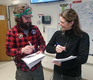 Man in checked shirt talking to woman in black jacket