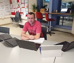 Stu in red shirt in front of many laptops