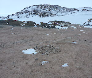 Pile of rock on the groiund and snowy hill in rear