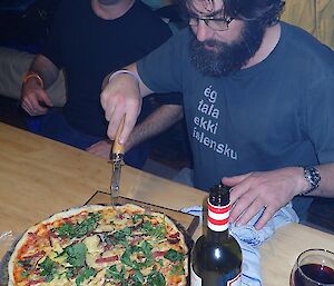 Expeditioners in a hut cutting pizza