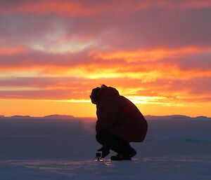 Expeditioner in front of sunset taking a picture