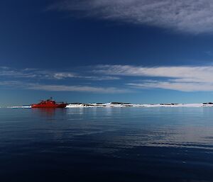 Aurora Australis on calm water with bergs in rear