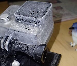 A frozen camera housing sitting on a bench.