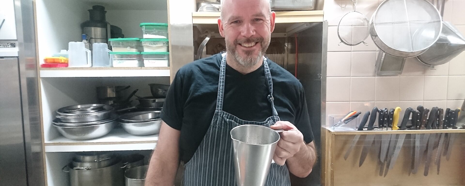 Andrew the chef holding a jug in the kitchen.