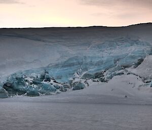 an ice cliff with pale blue ice