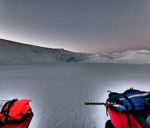 A cave in ice cliff and two quads in foreground.