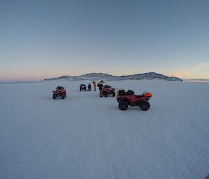 Quads on sea ice with team drilling ice.
