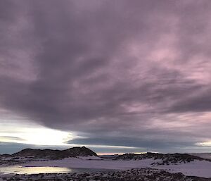 Pink night sky over hills and snow.