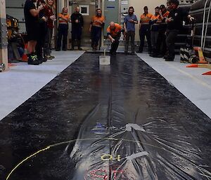 Group of expeditioners watching curling on black plastic