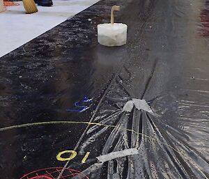 Curling ice block on black plastic sheeting