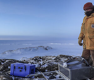 Stu in yellow jacket on top of a hill with sea ice in background