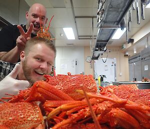 Chef and Mat in the kitchen with lobsters on the bench.