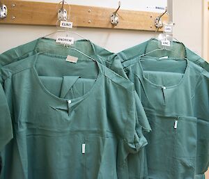 Four sets of scrubs on coat hangers.
