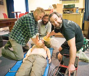 Three expeditioners and a resuscitation mannequin.