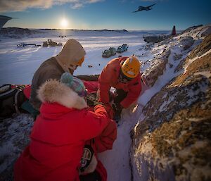 SAR training excercise showing expeditioners tending to an injured person on a rocky slope.